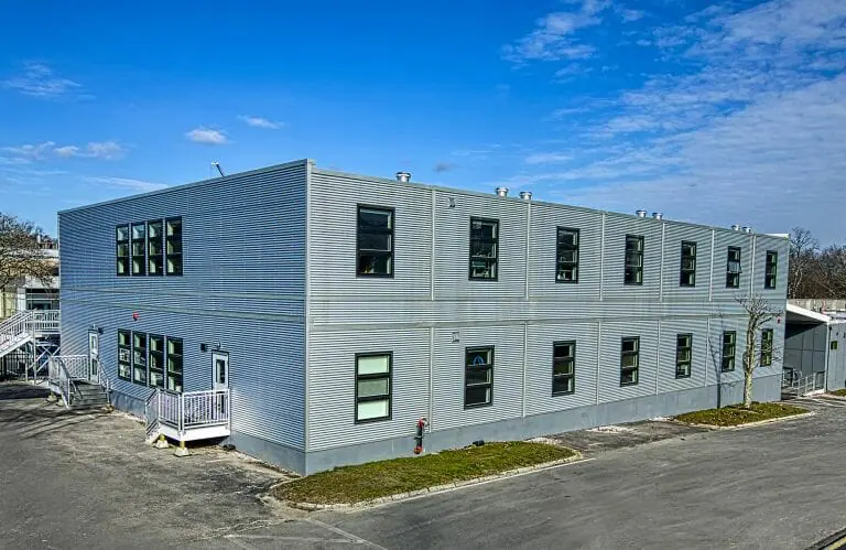 Edifício modular de dois andares com revestimento de metal ondulado galvalume, janelas com classificação Energy Star e HVAC avançado para ventilação de ar fresco, projetado para um cliente de biotecnologia de Massachusetts para maximizar a ocupação e a sustentabilidade