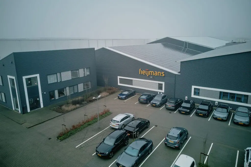 Aerofilm-Heijmans-Heereveen_DJI_0353_1200x800-1024x683.jpg.webp Instalação de construção modular da Heijmans na Holanda, apresentando soluções modernas de construção pré-fabricada com telhado integrado à energia solar e design sustentável.