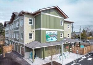 Edifício modular permanente de três andares com revestimento verde e grande mural.