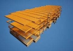 Grande estrutura industrial de aço amarela vista de baixo contra um vasto céu azul.